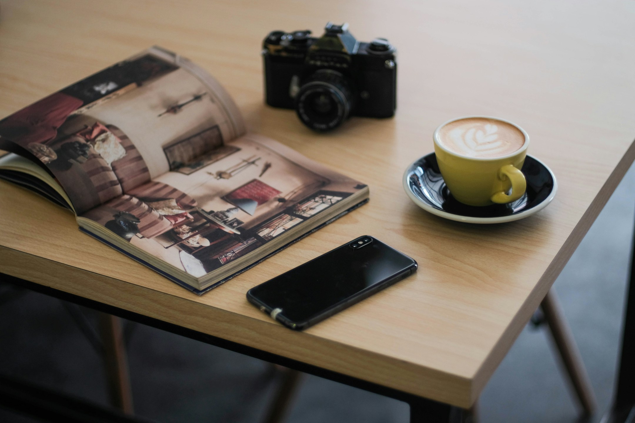 Coffee and phone on an intimate table, soft natural light, the still moment before the day starts.