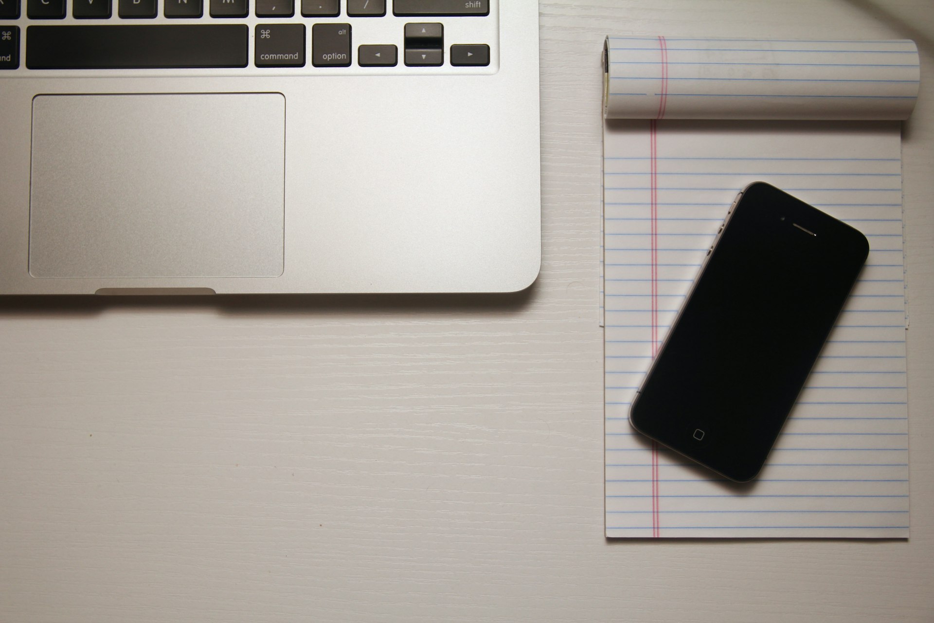 An old laptop with the cover closed and a newer phone resting on top of it, the visual of the operational simplification that comes from switching to a hosted product.