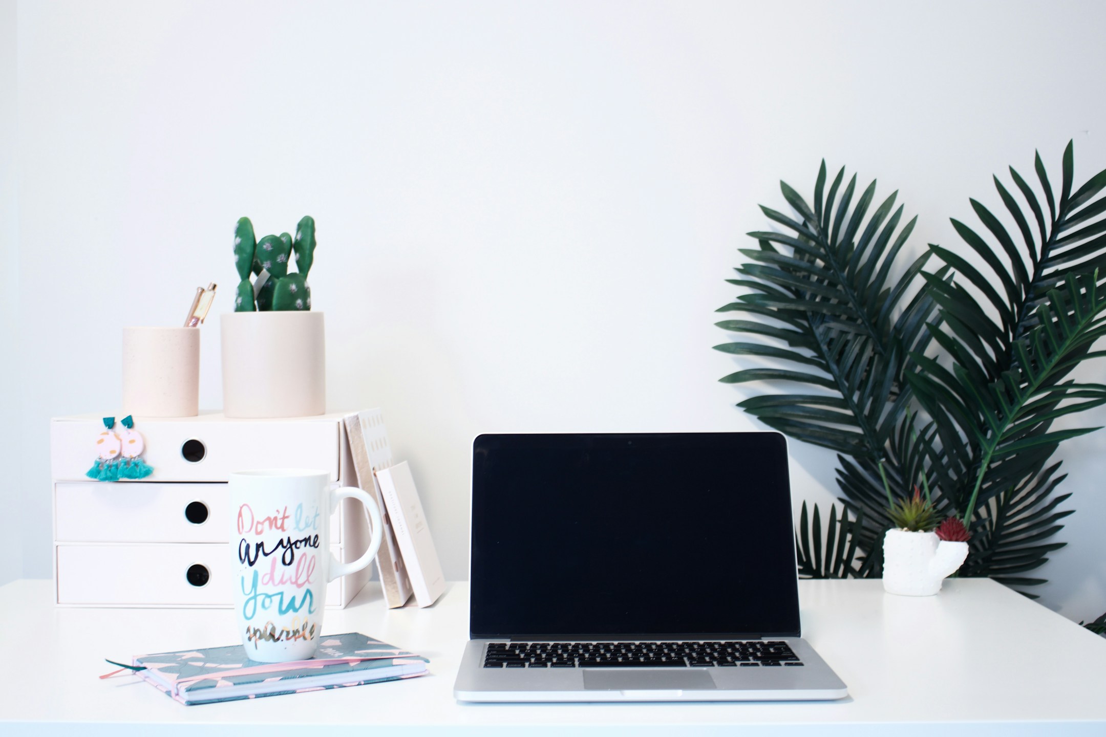 A MacBook, a mug, a notebook on a clean wooden desk. The visual of work routinized into something the agent now does.