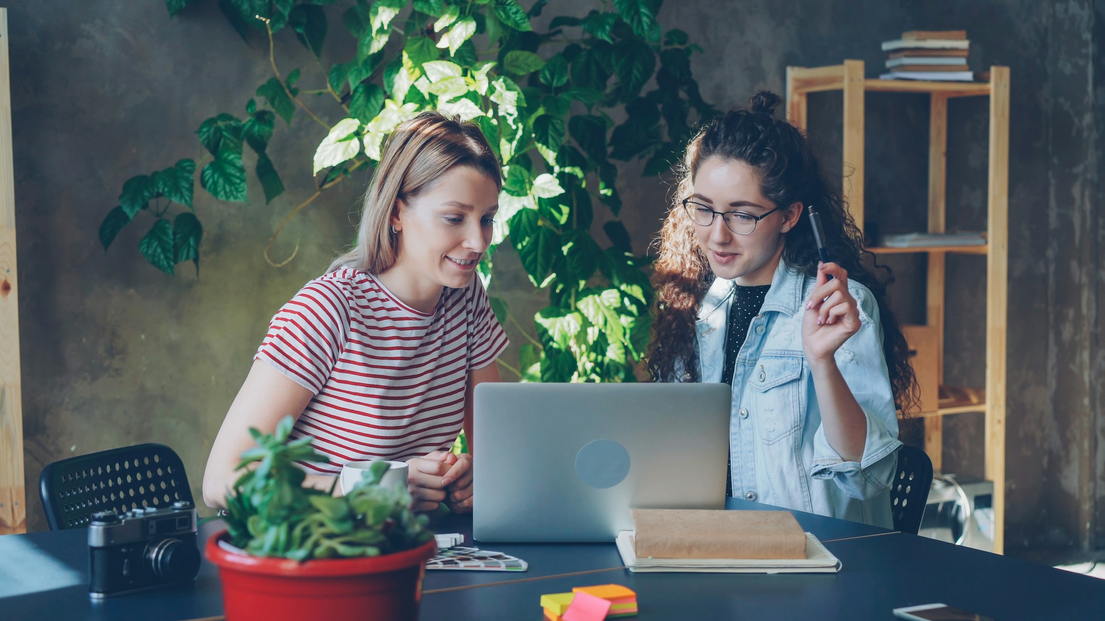Two women collaborating on a laptop, the human work that gets handled while the agent handles the calls.
