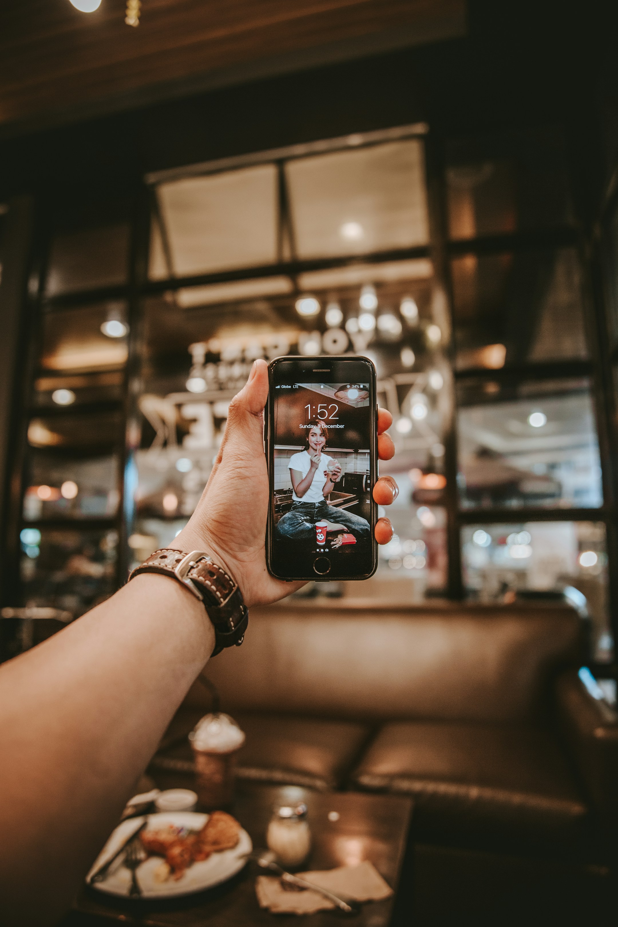 An iPhone in hand at a bar with moody bokeh, the visual of a phone in casual use, ready for new contacts to land.