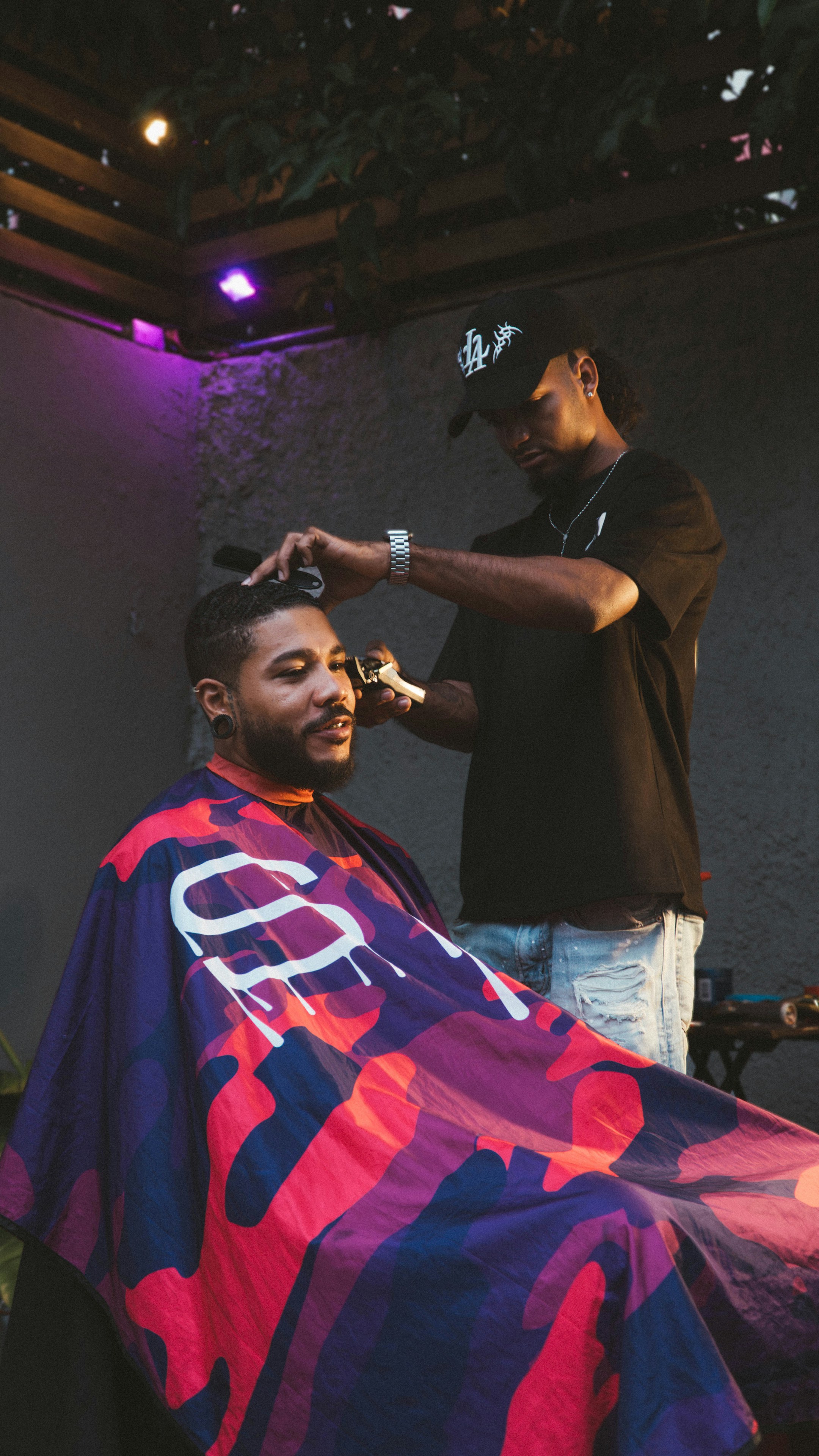 A barber working in a colorful shop. Customers call this number to book chairs, and an AI voice receptionist takes the booking when the barber is busy.