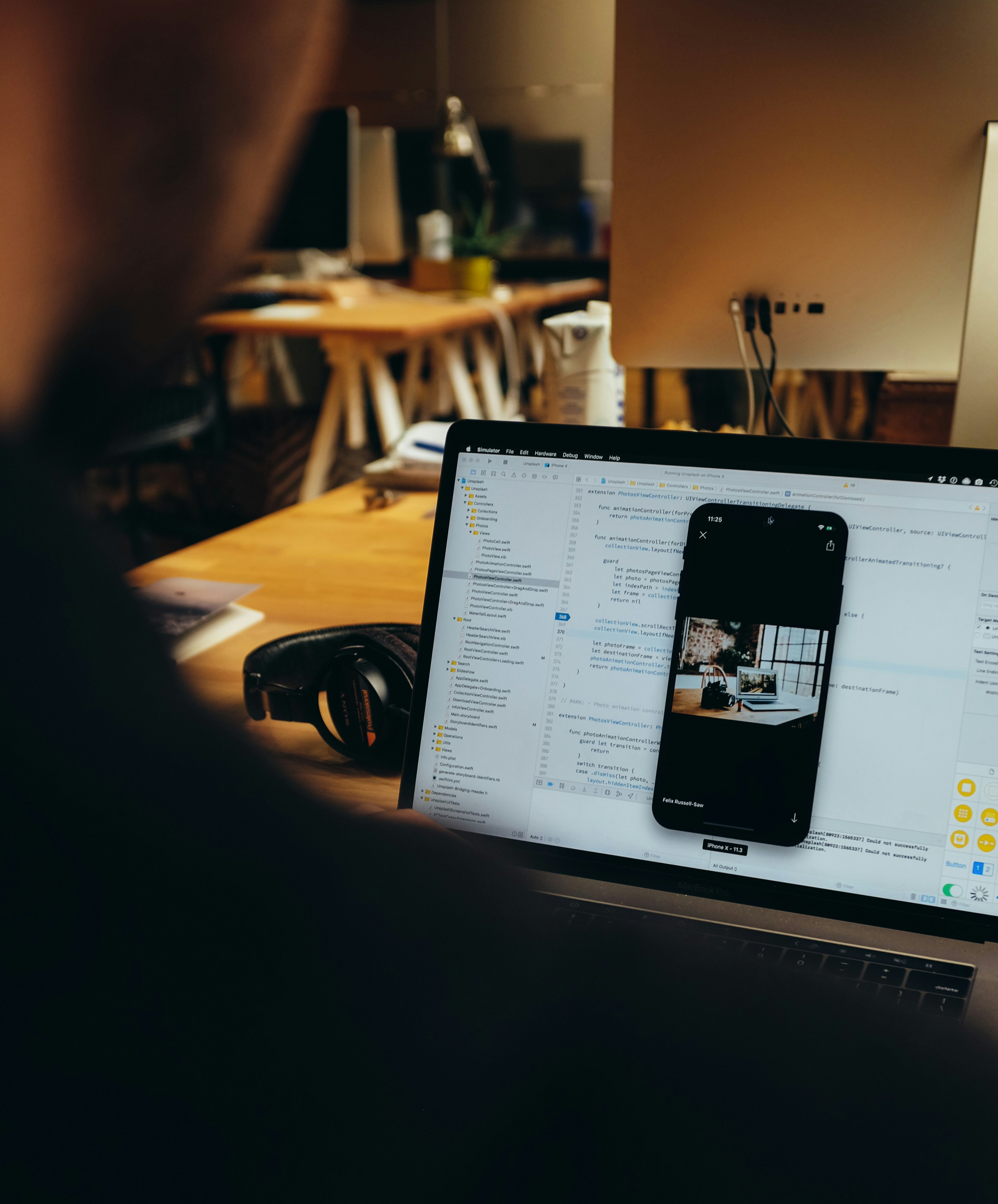 A developer working in Xcode with an iPhone simulator on screen.