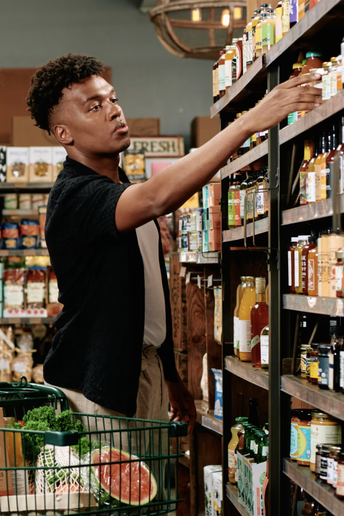 A grocery store owner reaching for a shelf -- an SMB that uses Ajeris to take calls.