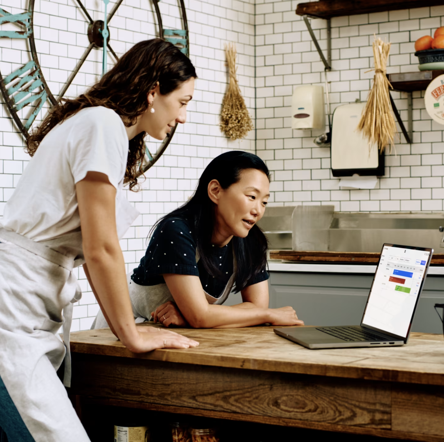 Two business owners reviewing a laptop together, mid-introduction.